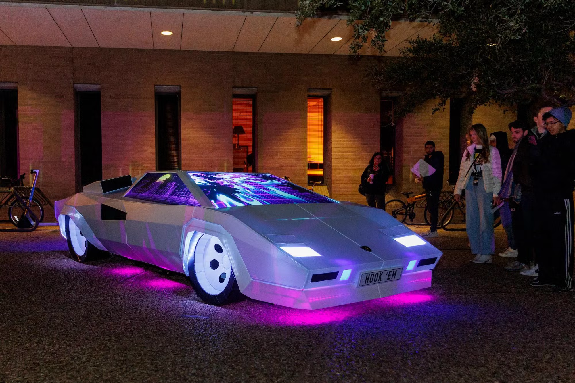 Life-size Countach installation glowing with purple and blue projections and pink underlighting at UT Austin.
